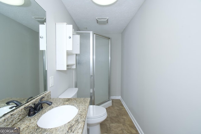 bathroom with a shower with door, vanity, a textured ceiling, and toilet