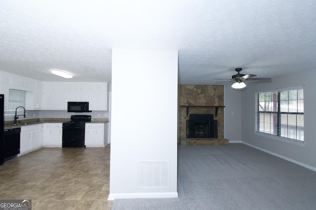 kitchen with white cabinetry, ceiling fan, sink, a fireplace, and black appliances