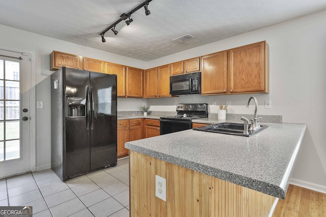 kitchen with kitchen peninsula, rail lighting, sink, black appliances, and light tile patterned floors