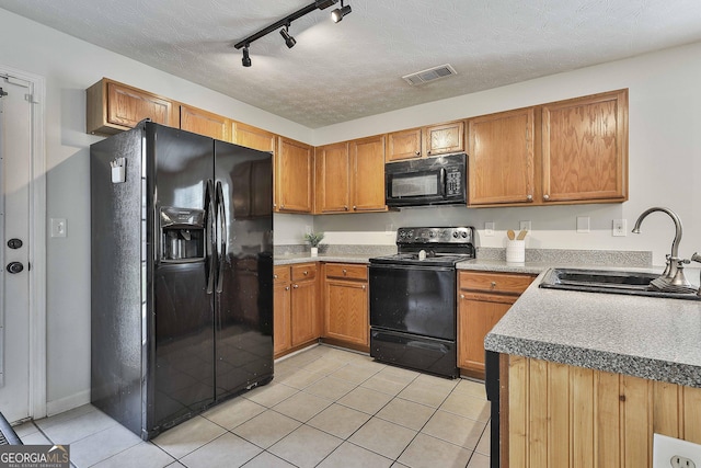 kitchen featuring sink, rail lighting, black appliances, and a textured ceiling