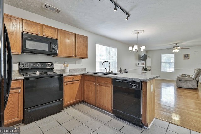 kitchen with black appliances, light hardwood / wood-style floors, sink, and a textured ceiling