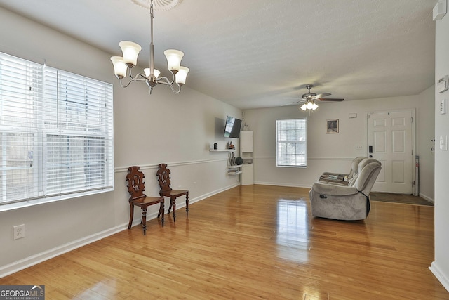 sitting room featuring ceiling fan with notable chandelier and light hardwood / wood-style flooring