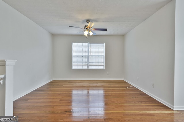 empty room with ceiling fan, wood-type flooring, and a textured ceiling