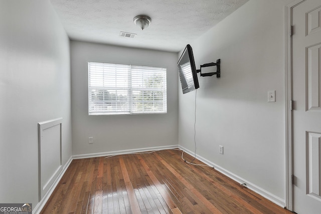 spare room with dark wood-type flooring and a textured ceiling