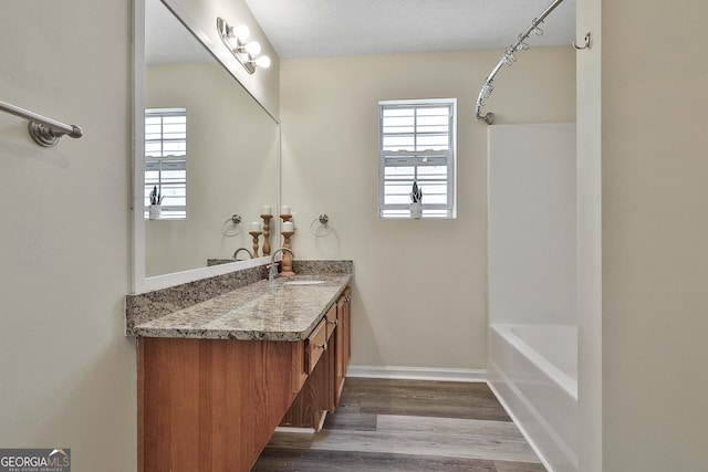 bathroom featuring shower / bathing tub combination, wood-type flooring, vanity, and a textured ceiling