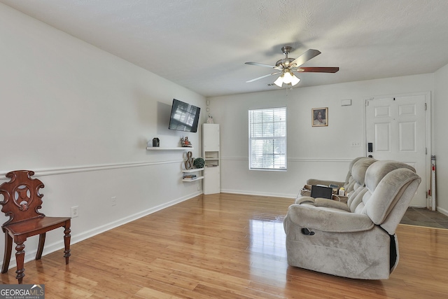 living area featuring light wood-type flooring and ceiling fan