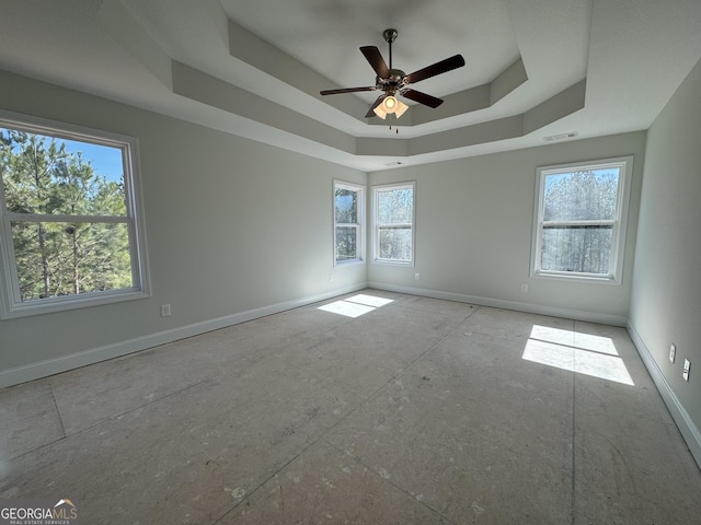 unfurnished room featuring a tray ceiling, a ceiling fan, visible vents, and baseboards