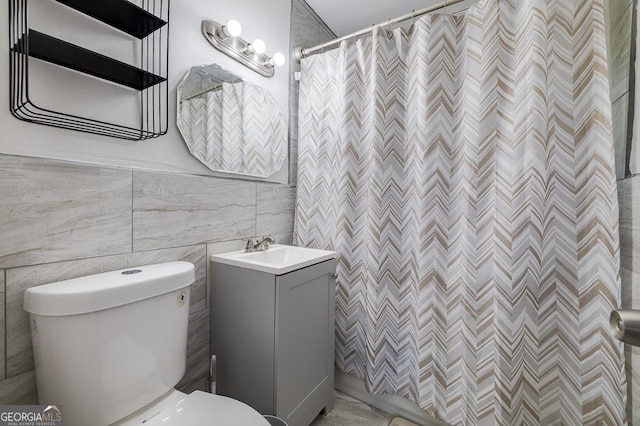 bathroom with curtained shower, vanity, tile walls, and toilet