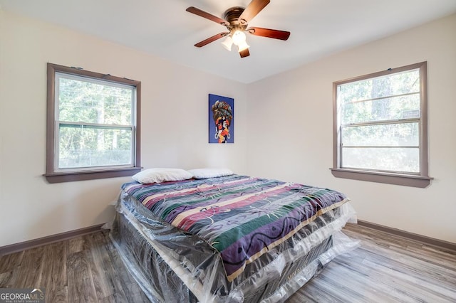 bedroom with hardwood / wood-style flooring, multiple windows, and ceiling fan