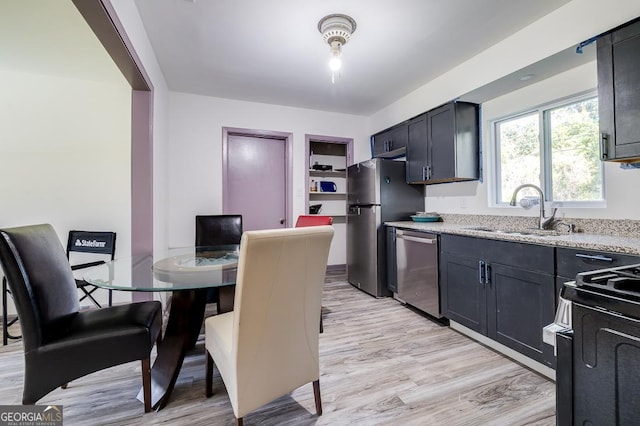 kitchen featuring light stone countertops, sink, light wood-type flooring, and appliances with stainless steel finishes