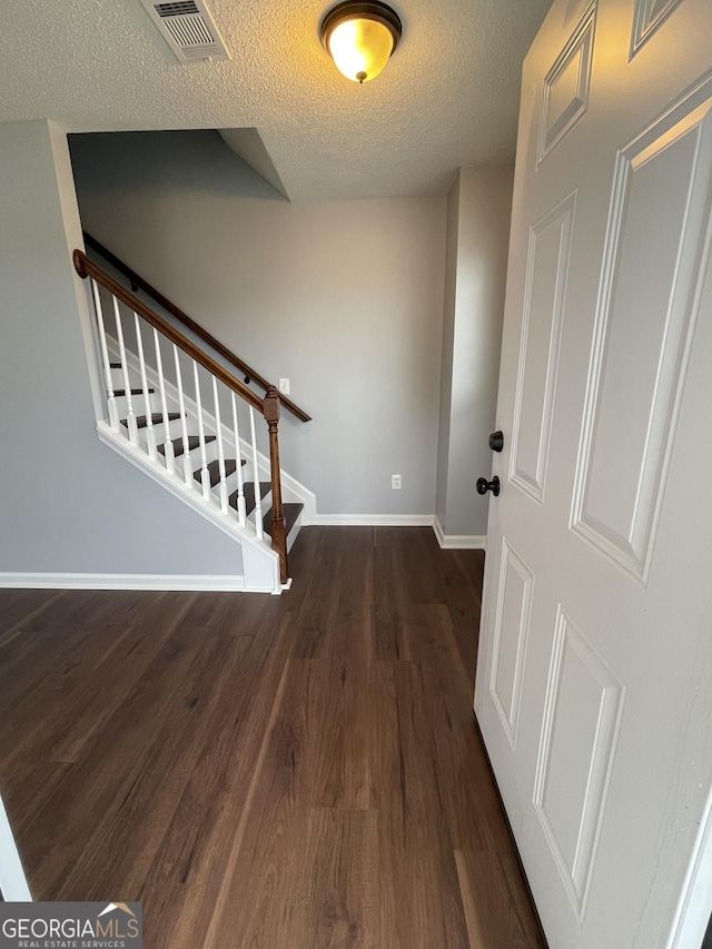 entryway featuring a textured ceiling and dark wood-type flooring