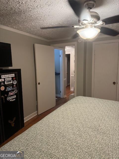 unfurnished bedroom with dark hardwood / wood-style flooring, a textured ceiling, ceiling fan, and crown molding