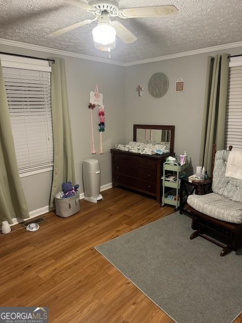 bedroom with ceiling fan, crown molding, a textured ceiling, and hardwood / wood-style flooring