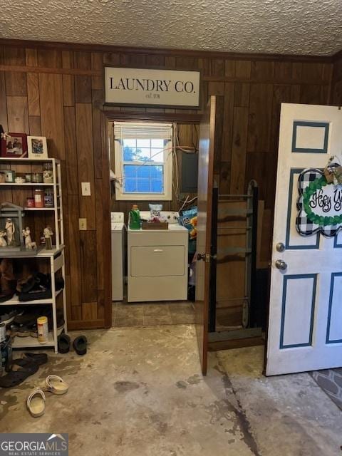 interior space featuring washer and dryer, a textured ceiling, and wood walls