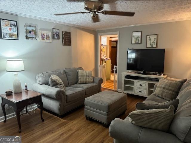 living room with ceiling fan, crown molding, a textured ceiling, and hardwood / wood-style flooring