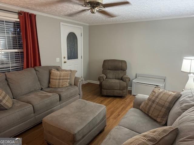 living room featuring hardwood / wood-style floors, a textured ceiling, ceiling fan, and ornamental molding