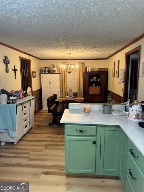 kitchen featuring an inviting chandelier, crown molding, green cabinetry, light wood-type flooring, and a textured ceiling