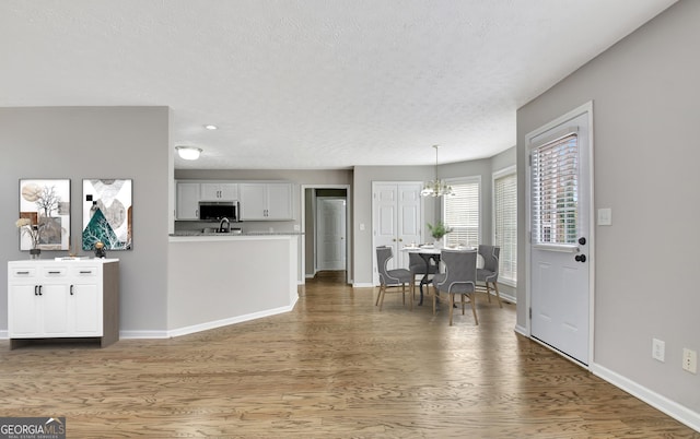 kitchen featuring white cabinetry, stainless steel microwave, light countertops, and wood finished floors