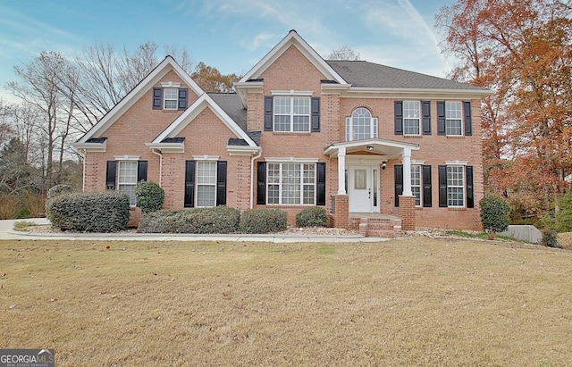 colonial inspired home with brick siding and a front lawn