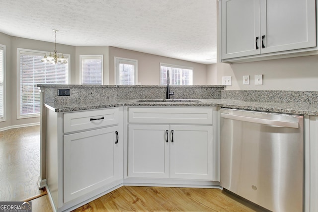 kitchen featuring light stone counters, stainless steel dishwasher, light wood-style flooring, a sink, and a chandelier