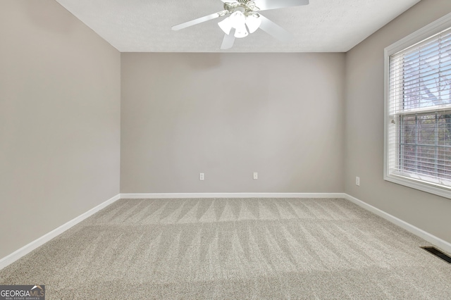 carpeted empty room featuring baseboards, visible vents, ceiling fan, and a textured ceiling