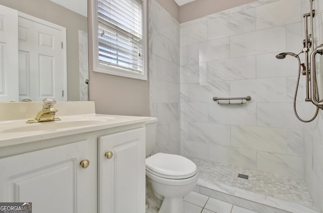 full bath with tiled shower, vanity, and toilet