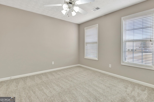 carpeted empty room with visible vents, ceiling fan, a textured ceiling, and baseboards