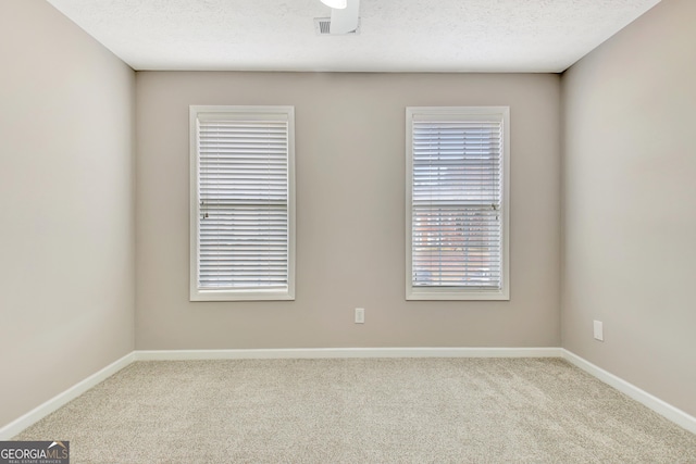 carpeted empty room with visible vents, a textured ceiling, and baseboards