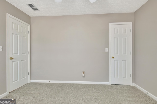 empty room featuring a textured ceiling, carpet floors, and visible vents