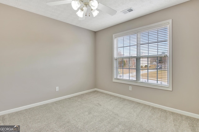 empty room with baseboards, visible vents, a ceiling fan, a textured ceiling, and carpet flooring