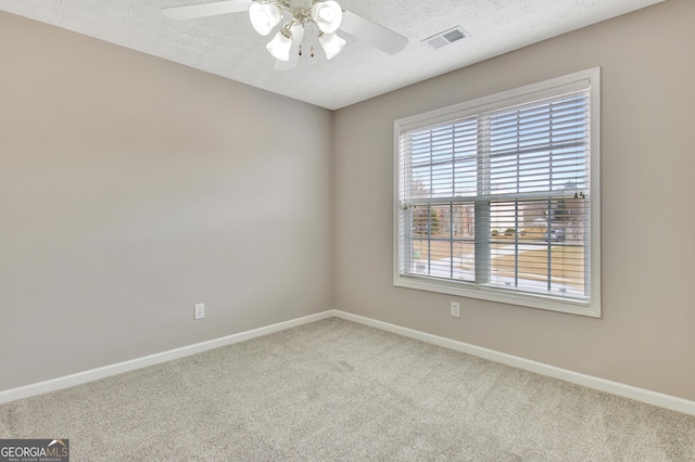 carpeted spare room featuring a textured ceiling, visible vents, ceiling fan, and baseboards