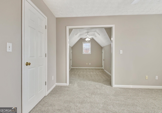 additional living space with vaulted ceiling, light carpet, ceiling fan, baseboards, and a textured ceiling
