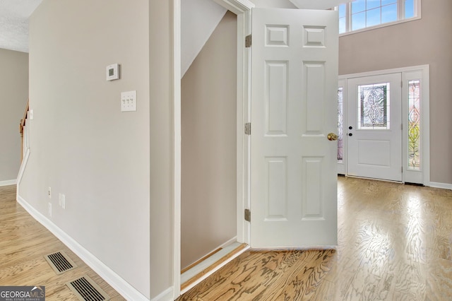 entryway with baseboards, visible vents, and wood finished floors