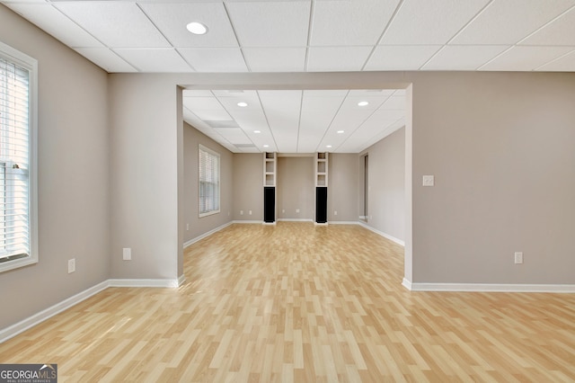 interior space featuring light wood-style floors, baseboards, a drop ceiling, and recessed lighting