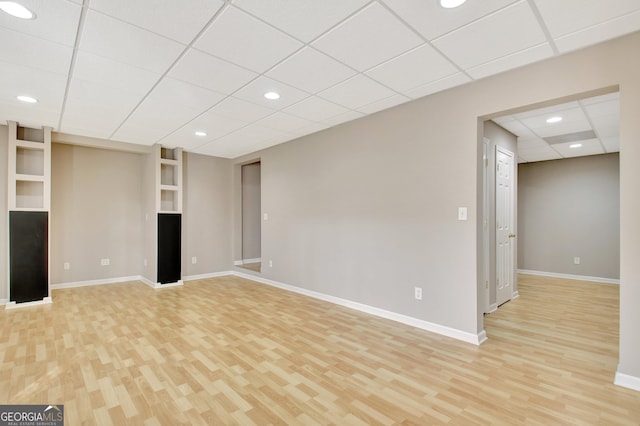 finished basement featuring light wood-type flooring, baseboards, a drop ceiling, and recessed lighting