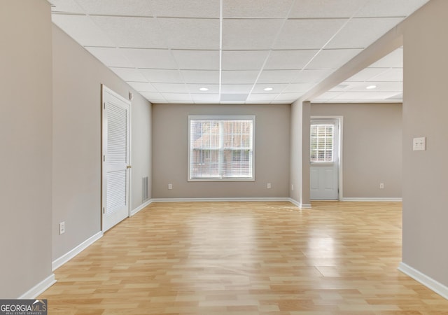 interior space featuring a paneled ceiling, visible vents, light wood-style flooring, and baseboards
