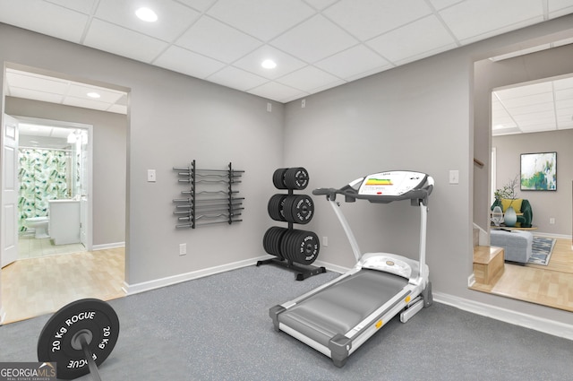 exercise area featuring a paneled ceiling, baseboards, and recessed lighting