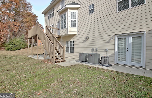 back of property with french doors, stairway, a lawn, a wooden deck, and a patio area