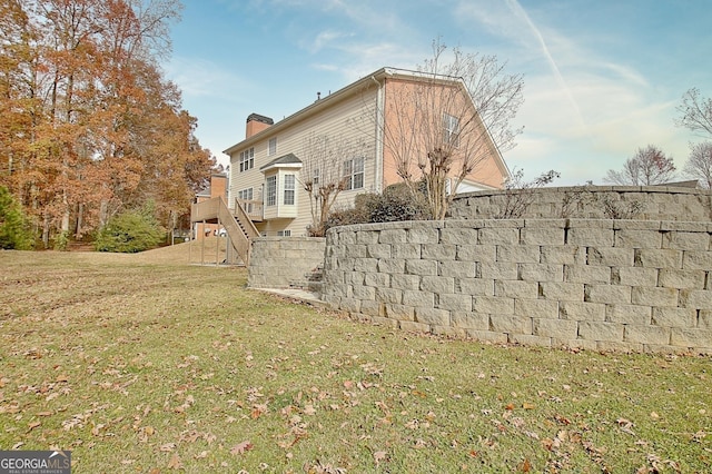 back of house featuring a lawn, stairway, and a chimney