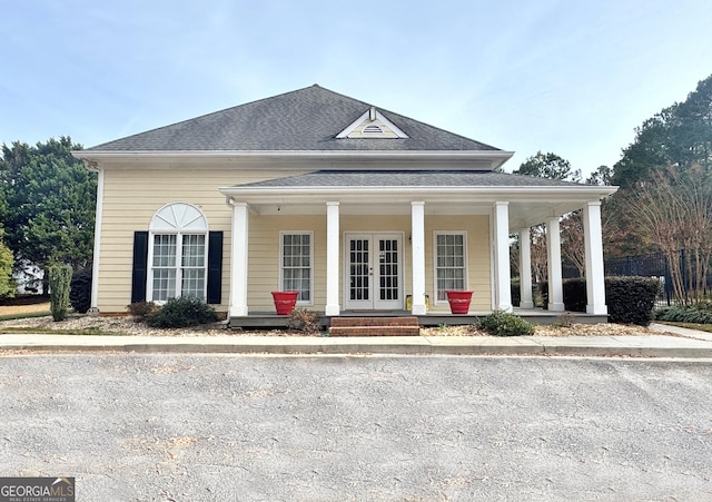 view of front of property with covered porch, french doors, and roof with shingles