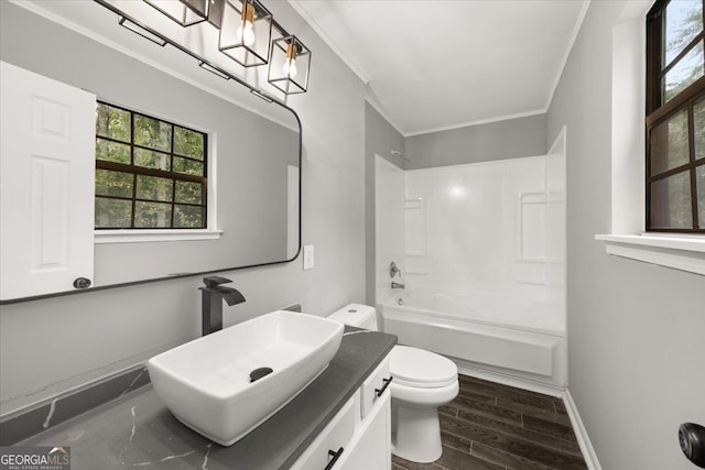 full bathroom featuring ornamental molding, vanity, hardwood / wood-style flooring, washtub / shower combination, and toilet