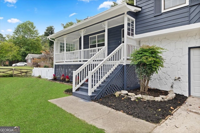 entrance to property with a porch and a lawn