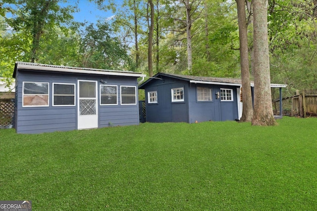 rear view of house with an outdoor structure and a lawn