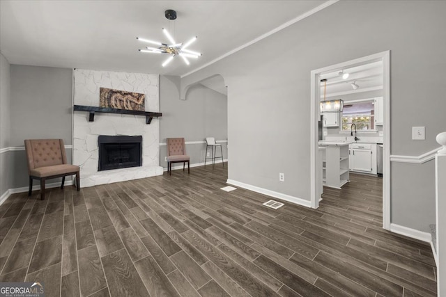 unfurnished living room featuring dark hardwood / wood-style floors, a fireplace, and an inviting chandelier