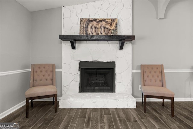 sitting room featuring hardwood / wood-style flooring, a stone fireplace, and vaulted ceiling