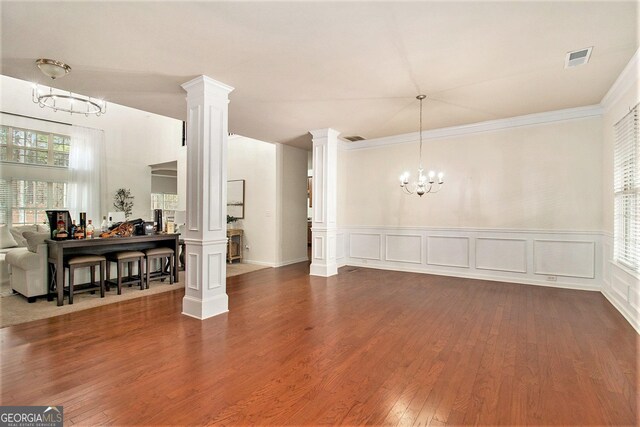 interior space with decorative columns, a chandelier, dark hardwood / wood-style floors, and ornamental molding