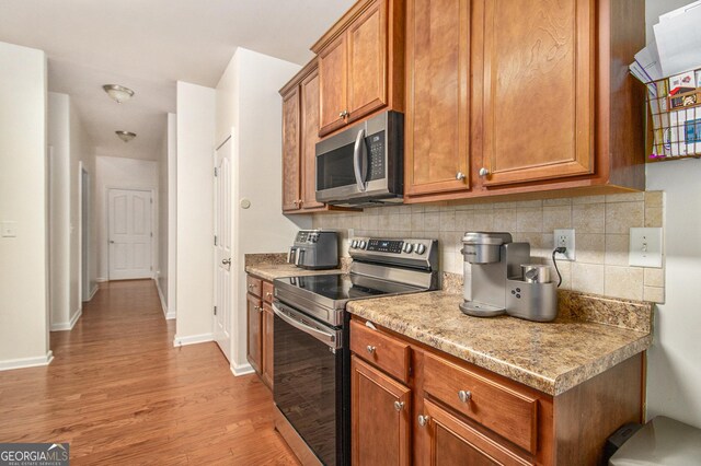 kitchen featuring tasteful backsplash, light wood-type flooring, and appliances with stainless steel finishes