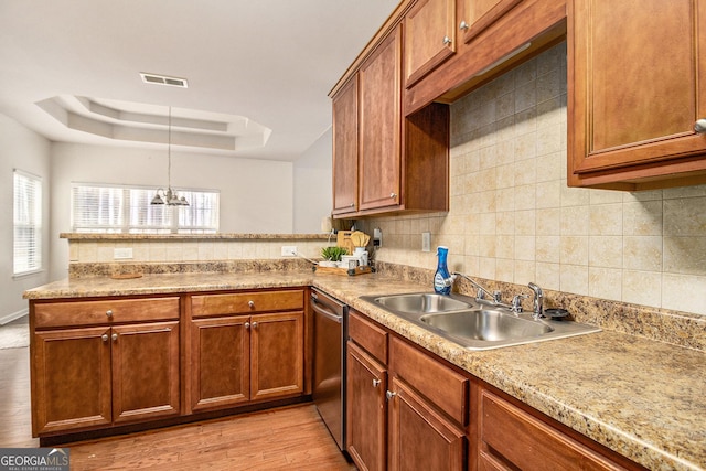 kitchen featuring a sink, visible vents, light countertops, dishwasher, and a tray ceiling