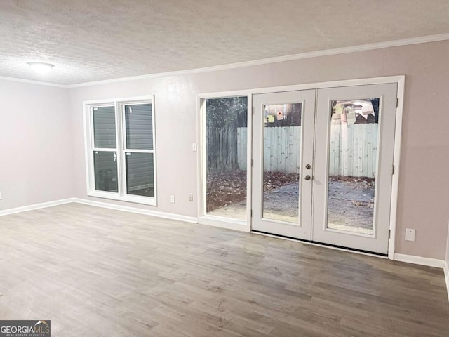 unfurnished room with a textured ceiling, wood-type flooring, crown molding, and french doors