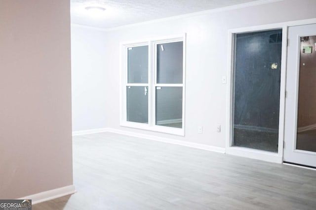 empty room with hardwood / wood-style floors, a textured ceiling, and crown molding